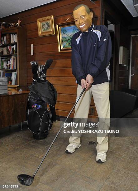 An employee of Japanese toy mask maker Ogawa Rubber wears a rubber mask resembling US top golfer Tiger Woods at the company's factory in Saitama,...