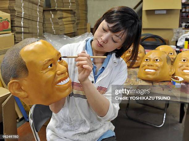 An employee of Japanese toy mask maker Ogawa Rubber, paints eyes on a rubber mask resembling US top golfer Tiger Woods at the company's factory in...