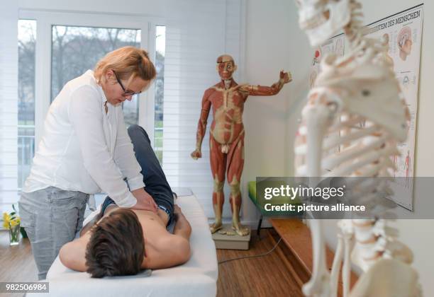 Christina Grosse Boymann, healing practitioner, osteopath and physiotherapist, treating a young man at her practice in Frankfurt an der Oder,...