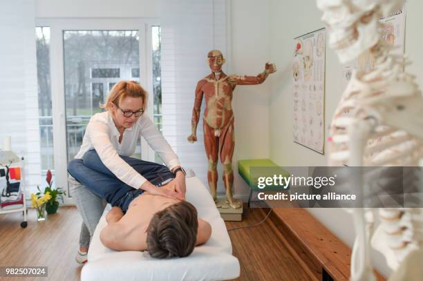 Christina Grosse Boymann, healing practitioner, osteopath and physiotherapist, treating a young man at her practice in Frankfurt an der Oder,...