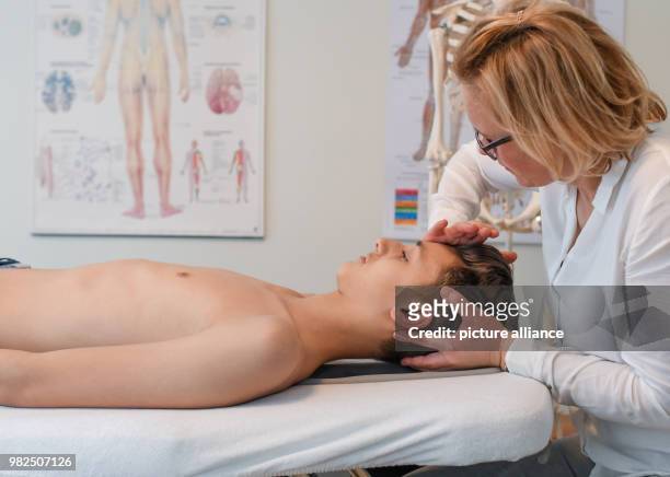 Christina Grosse Boymann, healing practitioner, osteopath and physiotherapist, treating a young man at her practice in Frankfurt an der Oder,...