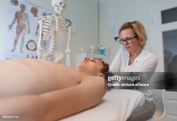 Christina Grosse Boymann, healing practitioner, osteopath and physiotherapist, treating a young man at her practice in Frankfurt an der Oder,...