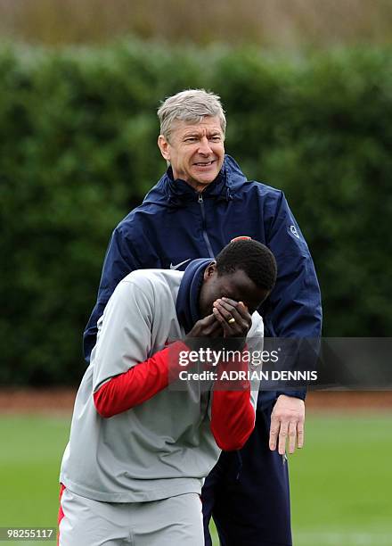 Arsenal's French coach Arsene Wenger smiles after colliding with Emmanuel Eboue during a training session at the club's complex in London Colney on...