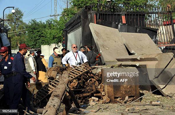 Consulate officials look at the damaged portion of thei consulate's main entrance following a suicide bomb attack in Peshawar on April 5, 2010....