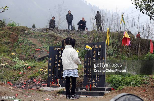 Young girl holding flowers mourns her father who died in the Sichuan earthquake on May 12 at the site of Xuankou Middle School on April 5, 2010 in...