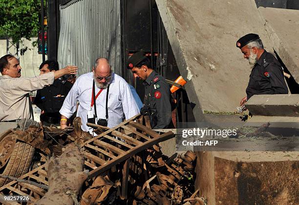 Consulate officials look at the damaged portion of their consulate's main entrance following a suicide bomb attack in Peshawar on April 5, 2010....