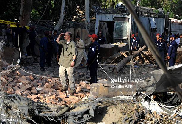 Consulate officials look at the damaged portion of the main entrance of their consulate following a huge suicide bomb attack in Peshawar on April 5,...