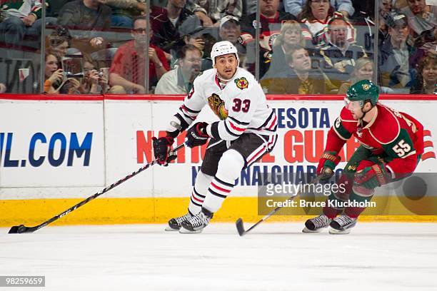 Dustin Byfuglien of the Chicago Blackhawks skates with the puck while Nick Schultz of the Minnesota Wild defends during the game at the Xcel Energy...