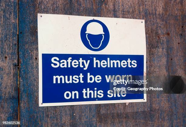 Safety helmets must be worn blue and white poster on a building site.