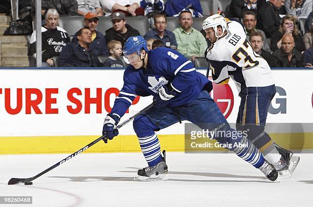 Luke Schenn of the Toronto Maple Leafs skates the puck away from Matt Ellis of the Buffalo Sabres during the game on April 1, 2010 at the Air Canada...