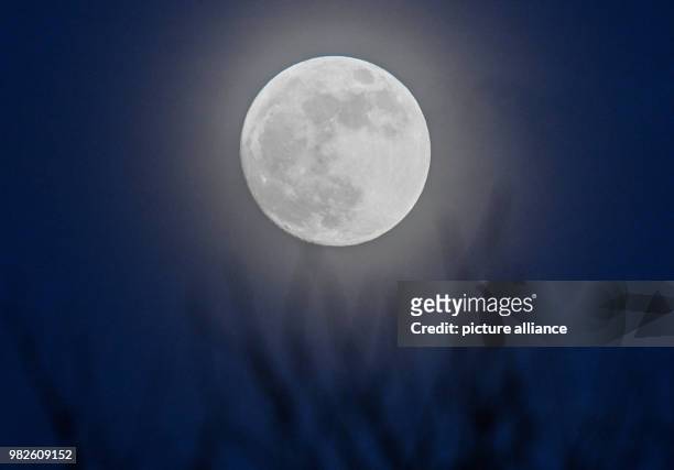The moon, 99 percent visible according to the moon calender, shining behind a thin cloud layer in Sieversdorf, Germany, 30 January 2018. The moon has...