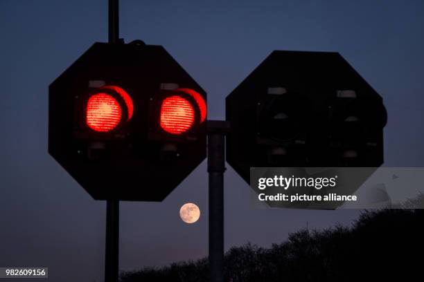 Dpatop - The moon shining behind signal lights of a sluice at the Ruhr river in Witten, Germany, 30 January 2018. The moon has three special...