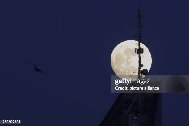 Full moon shines over a skyscraper in Leipzig, Germany, 30 January 2018. The full moon on 31 January 2018 will be a so-called supermoon. Photo: Jan...