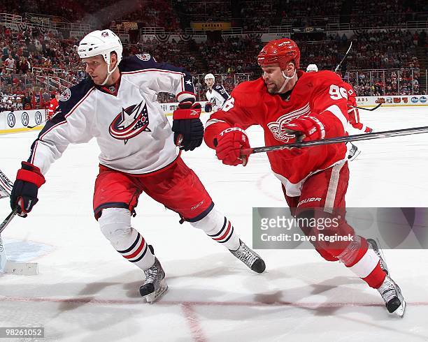 Marc Methot of the Columbus Blue Jackets reaches for the puck in front of Tomas Holmstrom of the Detroit Red Wings during an NHL game at Joe Louis...