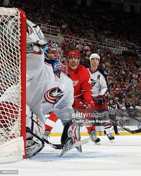 Steve Mason of the Columbus Blue Jackets makes a glove save as teammate RJ Umberger skates in behind Henrik Zetterberg of the Detroit Red Wings...