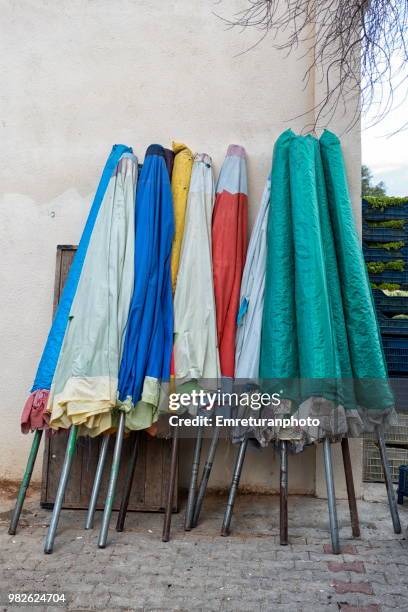 beach umbrellas piled up on a building wall. - emreturanphoto stock pictures, royalty-free photos & images