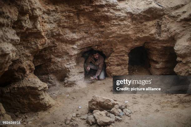 Palestinian Abdelkarim al-Kafarna, looks up as he sits in a discovered tomb consisting of nine burial holes, in his backyard in Beit Hanoun, Northern...