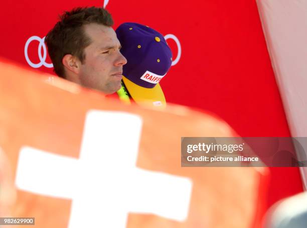 Winner Beat Feuz of Switzerland reacts behind a Swiss flag at the victory ceremony for the men's downhill event at the Ski World Cup in...