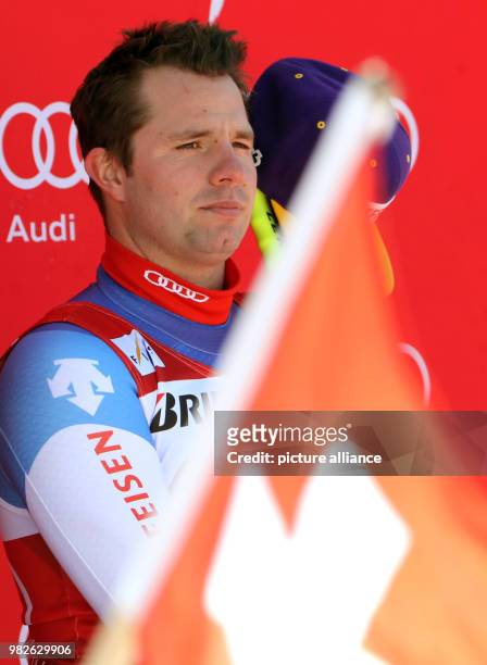Winner Beat Feuz of Switzerland reacts behind a Swiss flag at the victory ceremony for the men's downhill event at the Ski World Cup in...