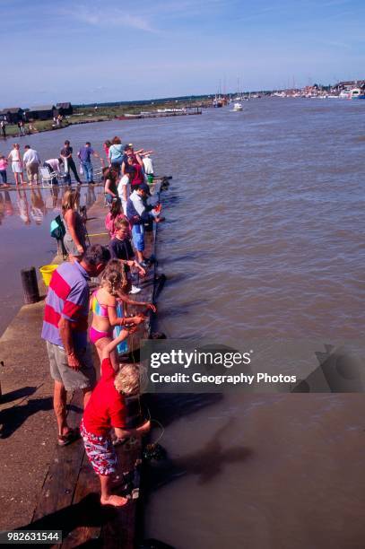 People crabbing high tide River blythe Walberswick Suffolk England.