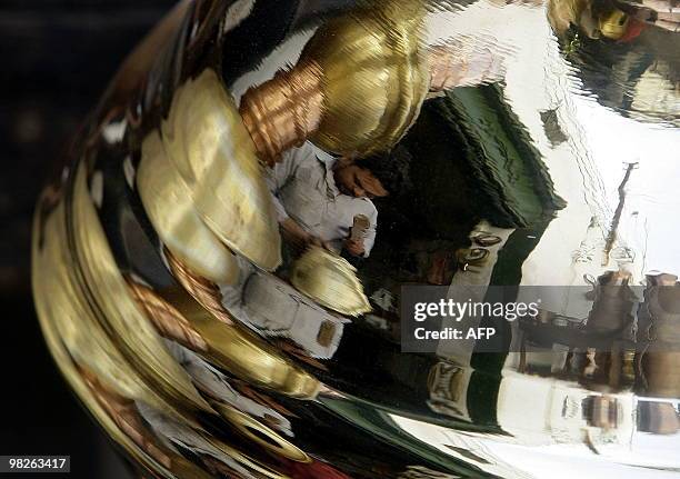 Libyan coppersmith is refelcted on a copper plate as he works at his workshop in the Tripoli's Old City on March 29, 2010. AFP PHOTO/JOSEPH EID