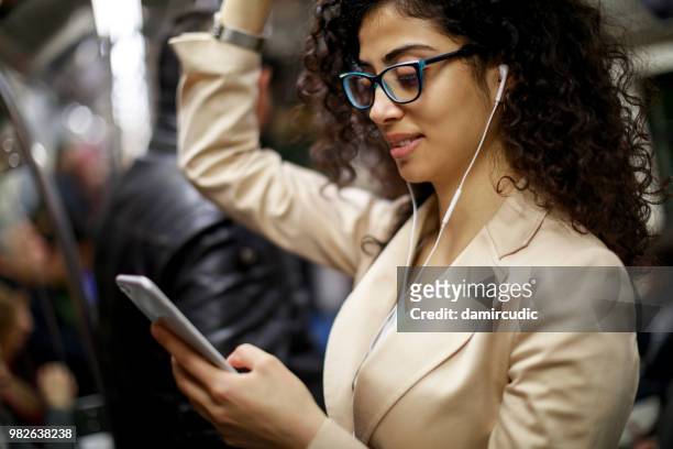 young businesswoman using smartphone while commuting to work by subway - damircudic stock pictures, royalty-free photos & images