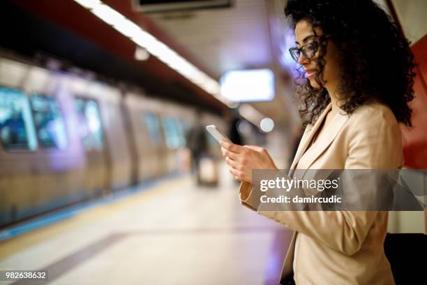 businesswoman using mobile phone on the subway station - damircudic stock pictures, royalty-free photos & images