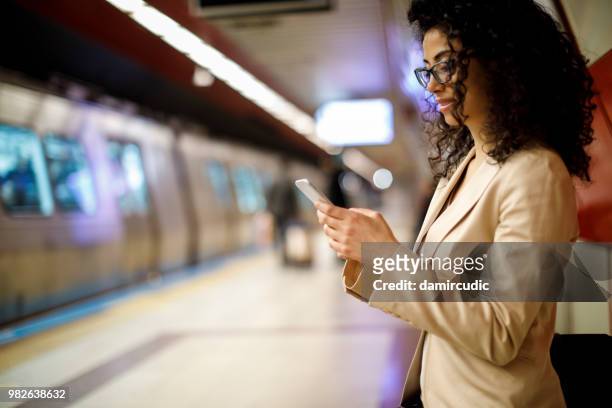 mulher de negócios usando o telefone celular na estação de metrô - damircudic - fotografias e filmes do acervo