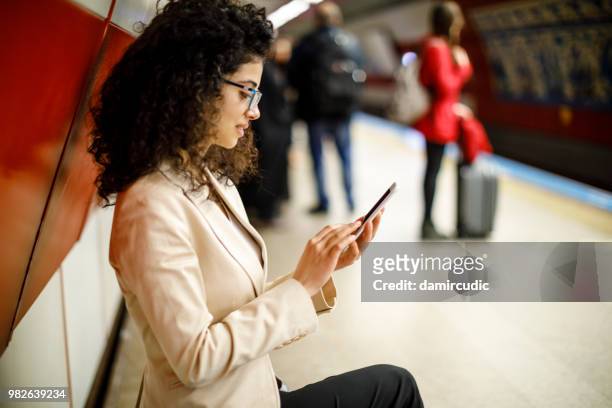 businesswoman using mobile phone on the subway station - damircudic stock pictures, royalty-free photos & images