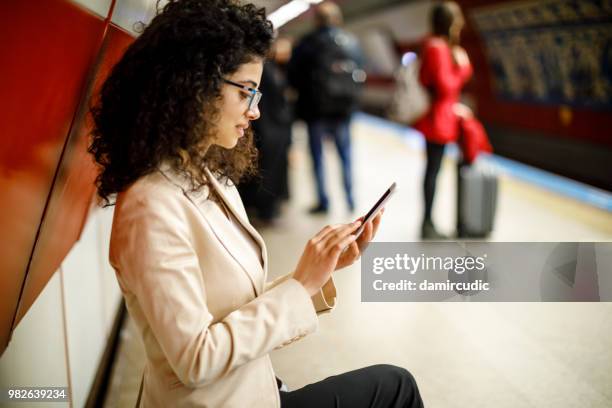 mulher de negócios usando o telefone celular na estação de metrô - damircudic - fotografias e filmes do acervo