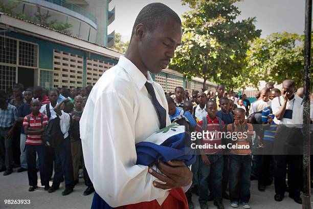 Andios Merizier holds the national flag during a prayer on the first day of school at the Lycee Marie Jeanne April 5, 2010 in Port-au-Prince, Haiti....