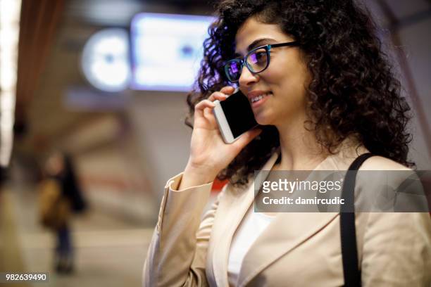 jovem empresária falando no celular na estação de metrô - damircudic - fotografias e filmes do acervo