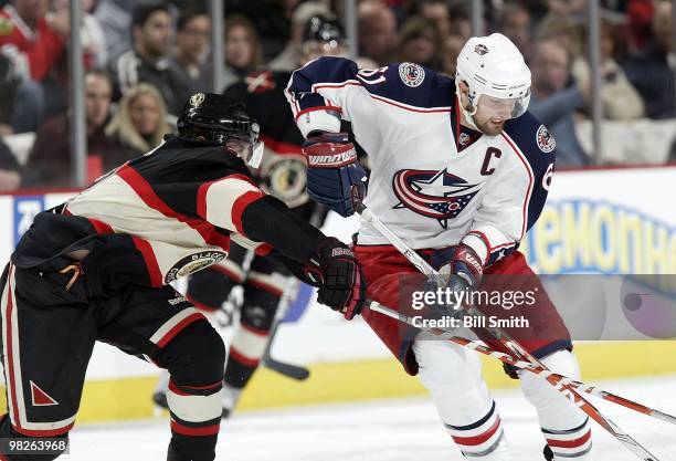 Rick Nash of the Columbus Blue Jackets approaches the puck as Duncan Keith of the Chicago Blackhawks reaches from behind during the game on March 28,...