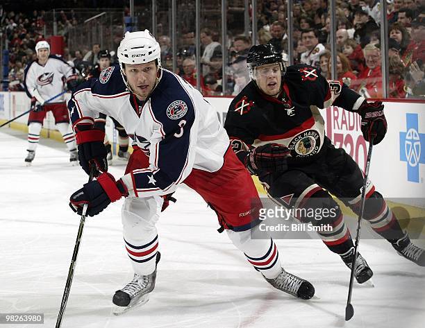 Marc Methot of the Columbus Blue Jackets and Kris Versteeg of the Chicago Blackhawks chase after the puck on March 28, 2010 at the United Center in...