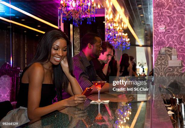 woman in nightclub bar reading message on phone - inti st clair stock pictures, royalty-free photos & images