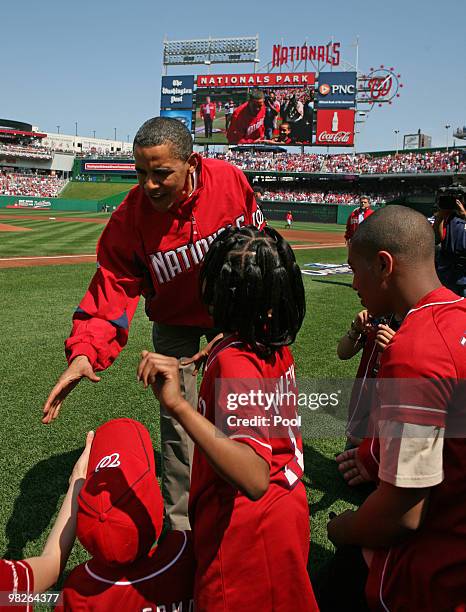 President Barack Obama is congratulated by kids on the sidelines at Nationals Stadium moments after he threw out the first pitch before the game...