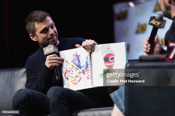 Actor Sebastian Stan reviews art created by a fan while on stage during a Civil War Cast conversation at ACE Comic Con at WaMu Theatre on June 23,...