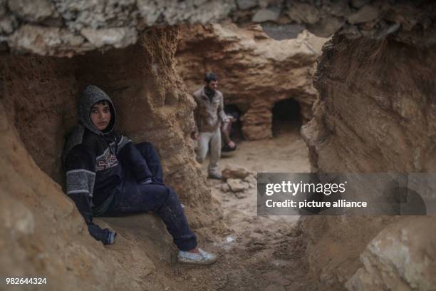 Dpatop - A Palestinian boy sits at a discovered tomb consisting of nine burial holes, in his backyard in Beit Hanoun, Northern Gaza City, 27 January...