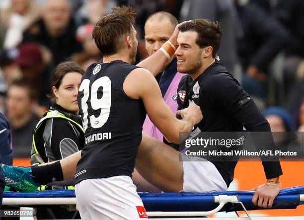 Lachie Plowman of the Blues is consoled by teammate Dale Thomas before leaving the field on a stretcher during the 2018 AFL round 14 match between...