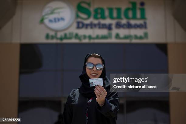 Reem, a Saudi driving instructor poses with her new Saudi driving license, on the first day after lifting the driving ban on women, at the Saudi...