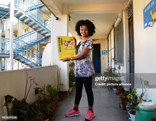 Bruktawit Tigabu, founder of the Whiz Kids Workshop media company, showing a small advertisement with her cartoon heroines in front of the offices of...