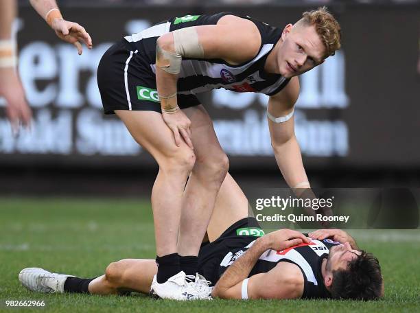 Adam Treloar of the Magpies checks on Levi Greenwood after he was bumped by Dale Thomas of the Blues during the round 14 AFL match between the...