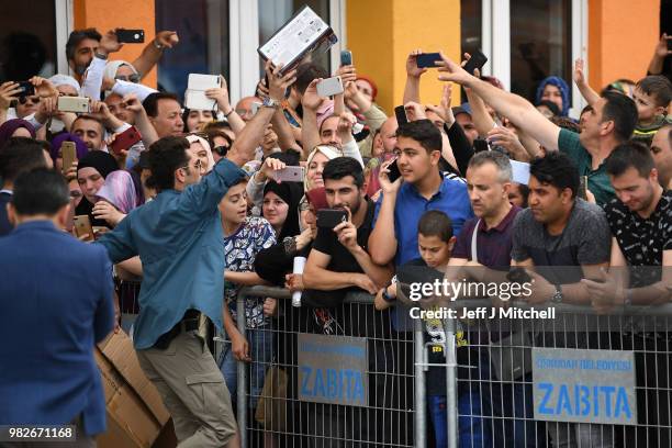 Supporters of President Recep Tayyip Erdogan are handed toys as they wait for his arrival at Saffet Cebi Ortaokulu polling station where he will cast...