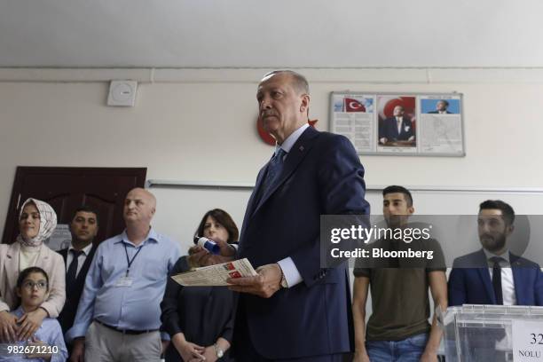 Recep Tayyip Erdogan, Turkey's president, holds his ballot papers as he prepares to vote at a polling station during parliamentary and presidential...