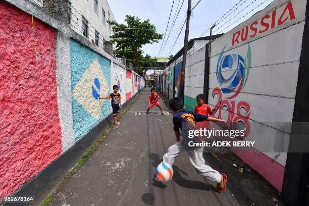 Indonesian children play street football along a village alley painted with murals related to the ongoing Russia 2018 World Cup football tournament,...