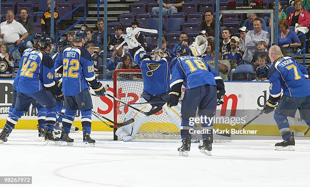 Ty Conklin of the St. Louis Blues stops pucks shot by teammates David Backes, Brad Boyes, Jay McClement and Keith Tkachuk during warmups before the...