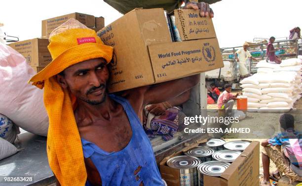 Yemeni civilians receive food aid for displaced people who fled battles in the Red Sea province of Hodeida and are now living in camps in the...