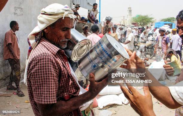 Yemeni civilian receives food aid for displaced people who fled battles in the Red Sea province of Hodeida and are now living in camps in the...