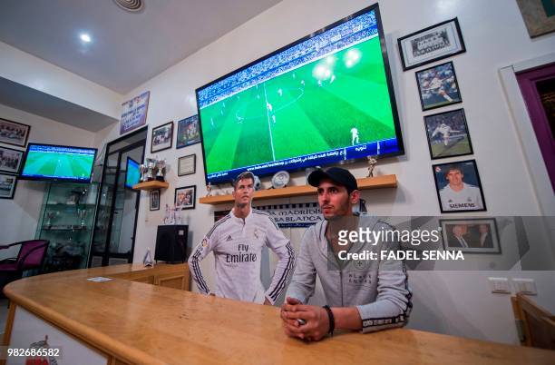 Supporter of Real Madrid football team stands next to a wooden cut-out of Cristiano Ronaldo, behind a reception counter at a Real Madrid's...