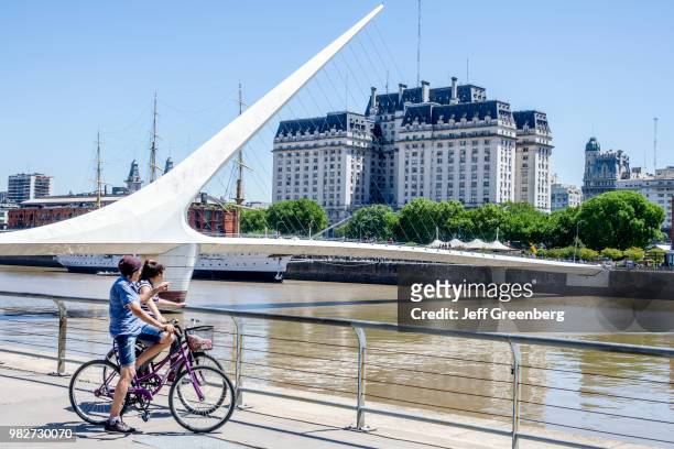 Teen girls on bicycles on the Puente De La Mujer, pedestrian suspension swing bridge.